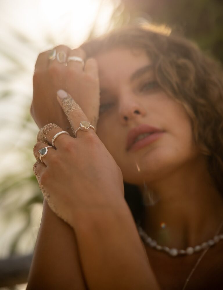 Hands holding a curated selection of raw gold rings and necklaces