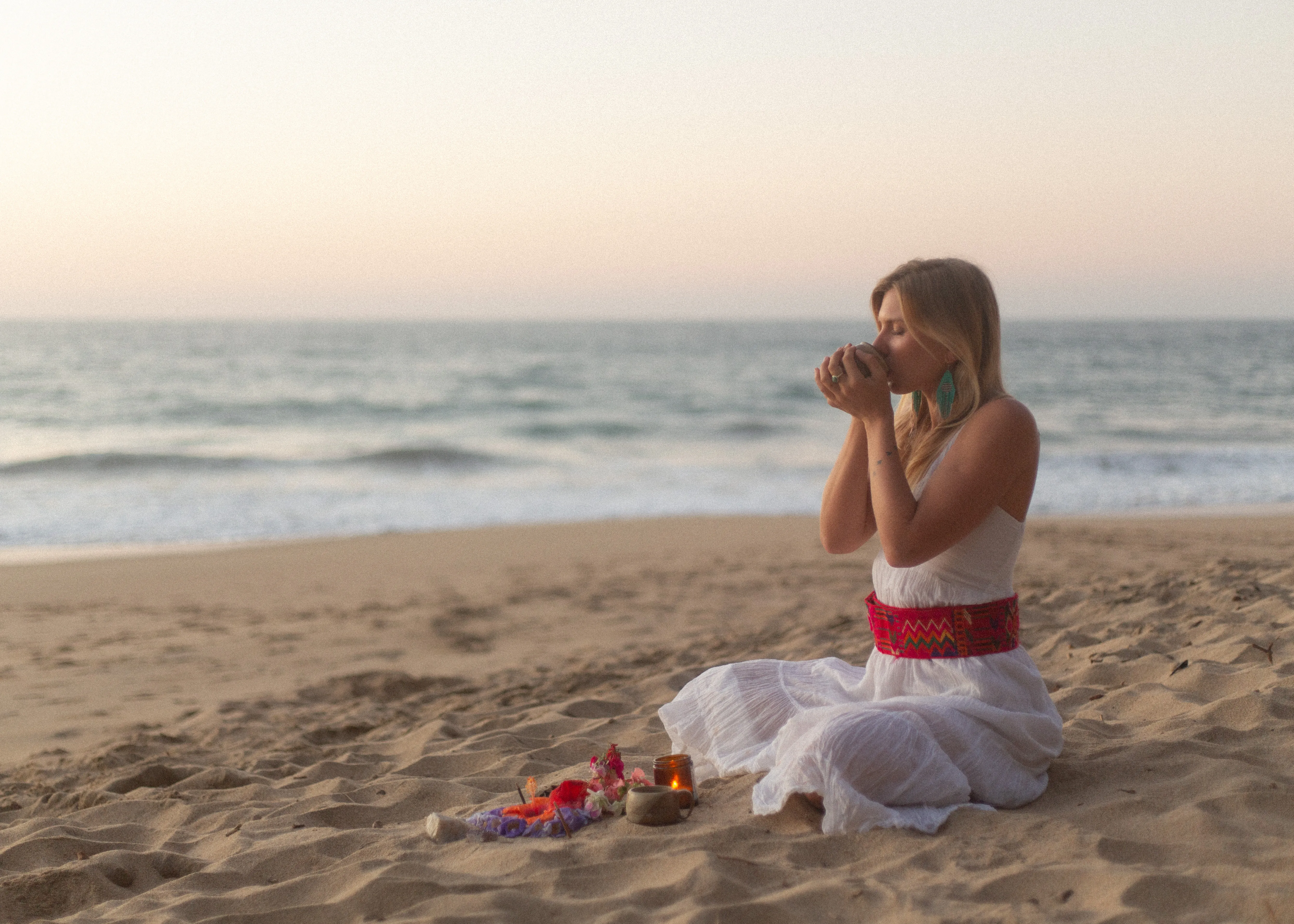 Woman drinking ceremonial cacao at sunrise on the beach